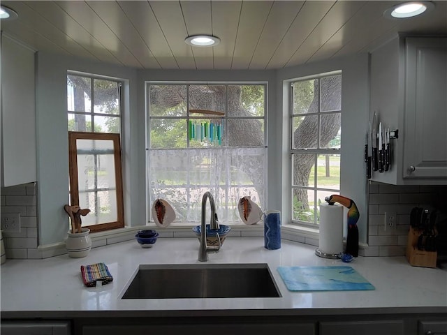 kitchen featuring white cabinets, backsplash, a wealth of natural light, and sink