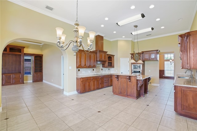 kitchen with light stone countertops, sink, hanging light fixtures, and a kitchen island