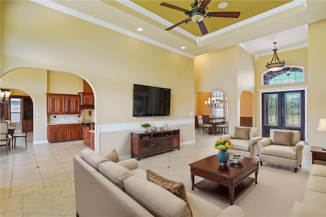 tiled living room featuring crown molding, a healthy amount of sunlight, a towering ceiling, and a raised ceiling