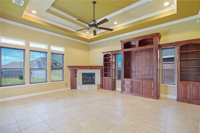 unfurnished living room with ornamental molding, a premium fireplace, and a raised ceiling