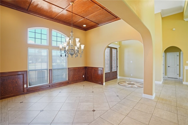 spare room with wooden ceiling, light tile patterned floors, a notable chandelier, and ornamental molding