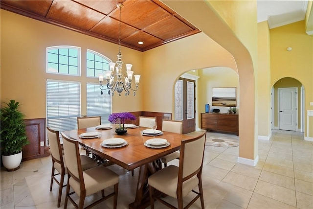 dining area featuring light tile patterned floors, a notable chandelier, crown molding, and wood ceiling