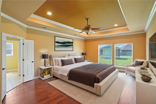 bedroom featuring ceiling fan, hardwood / wood-style flooring, a tray ceiling, and crown molding