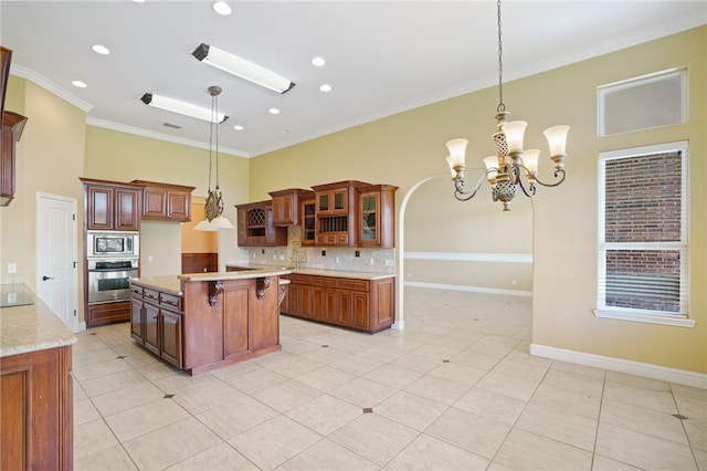 kitchen with crown molding, a kitchen breakfast bar, appliances with stainless steel finishes, decorative light fixtures, and a kitchen island