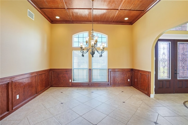 interior space featuring french doors, an inviting chandelier, ornamental molding, wooden ceiling, and light tile patterned floors