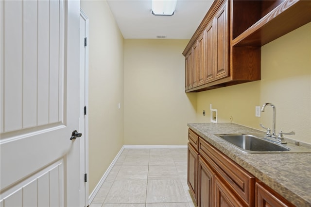 clothes washing area with sink, light tile patterned flooring, cabinets, and washer hookup