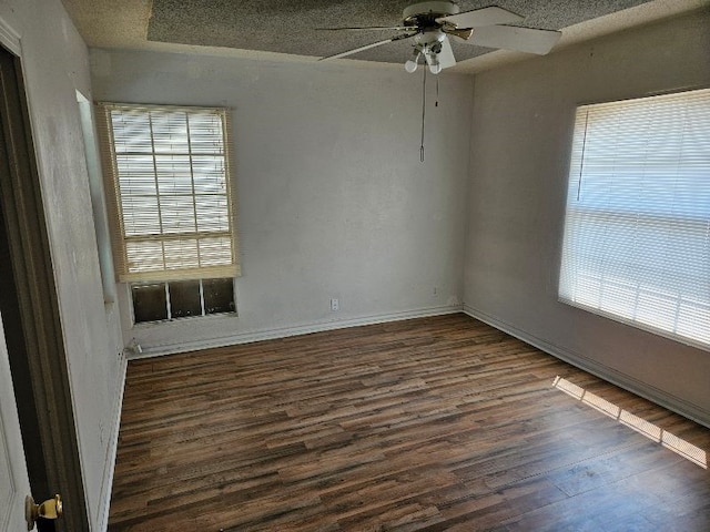 empty room with baseboards, a textured ceiling, dark wood-style floors, and a ceiling fan