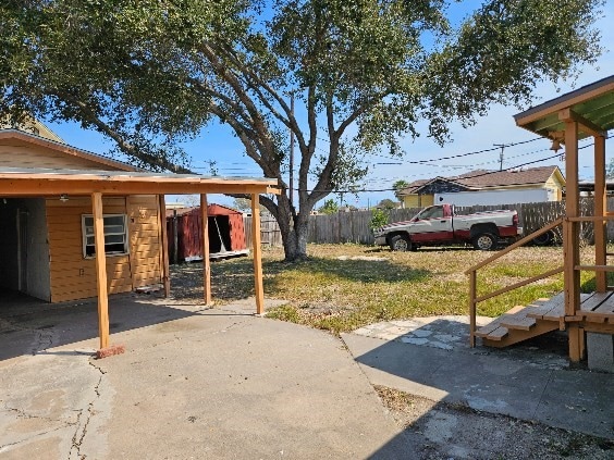 view of yard featuring a patio area, a carport, and fence