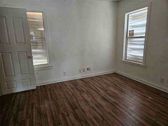 empty room featuring baseboards and dark wood-style flooring