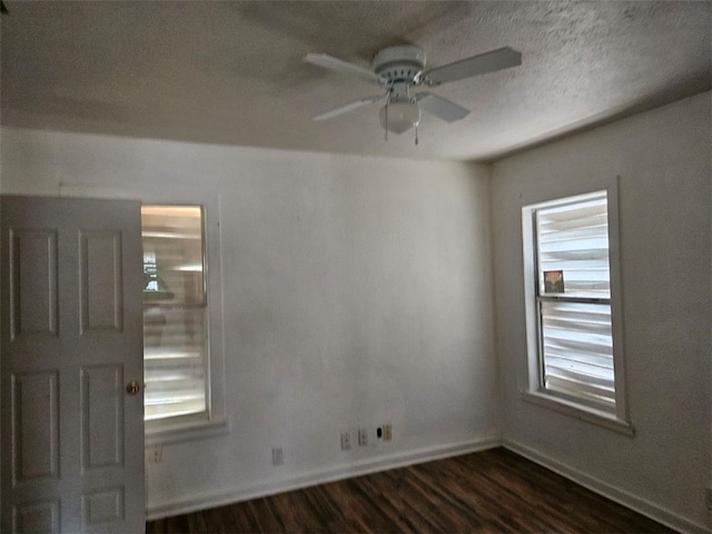 spare room with dark wood-style floors, ceiling fan, a textured ceiling, and baseboards