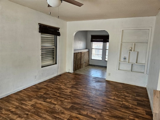 spare room featuring arched walkways, a textured ceiling, wood finished floors, and a ceiling fan