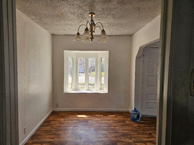 entrance foyer with dark wood-style floors, an inviting chandelier, a textured ceiling, and baseboards