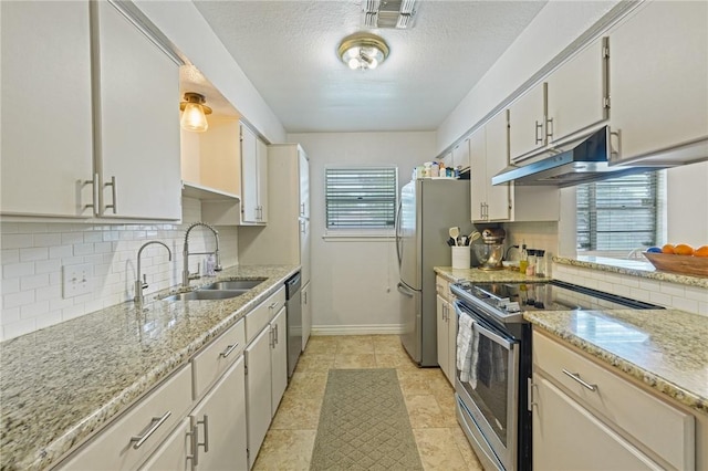 6205 Londonderry Dr, Corpus Christi, TX 78415 - kitchen with appliances with stainless steel finishes, under cabinet range hood, backsplash, light stone counters, and a textured ceiling