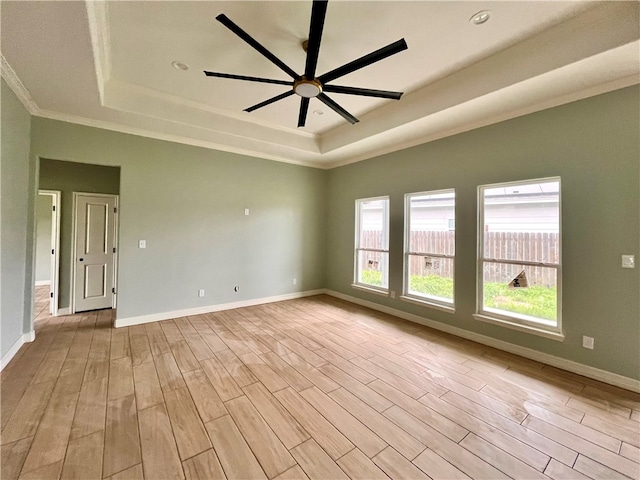 empty room featuring ornamental molding, ceiling fan, a tray ceiling, and light hardwood / wood-style floors