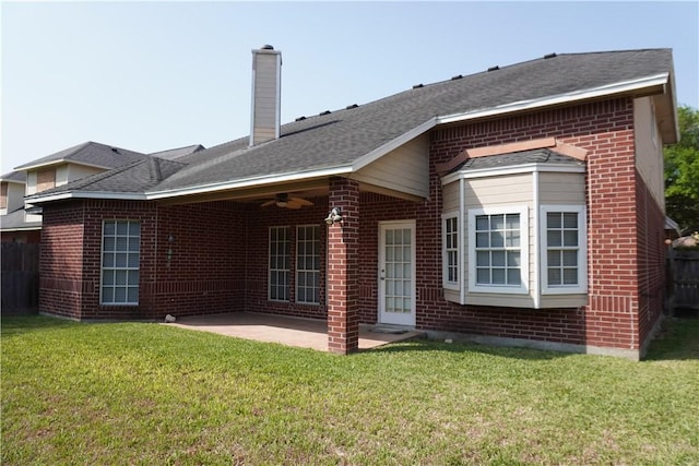 back of property with a patio area, a ceiling fan, brick siding, a yard, and a chimney