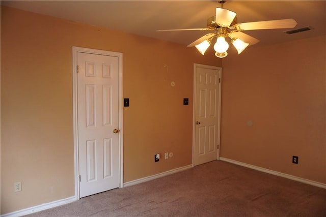 carpeted spare room with baseboards, ceiling fan, and visible vents