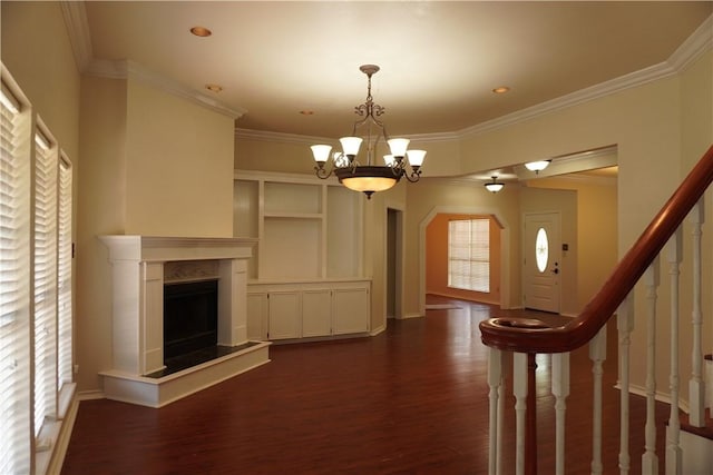 interior space featuring stairs, a chandelier, a fireplace, dark wood-type flooring, and ornamental molding