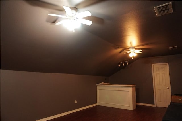 additional living space with vaulted ceiling, dark wood-type flooring, baseboards, visible vents, and ceiling fan