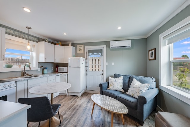 kitchen with plenty of natural light, white appliances, decorative light fixtures, and white cabinets