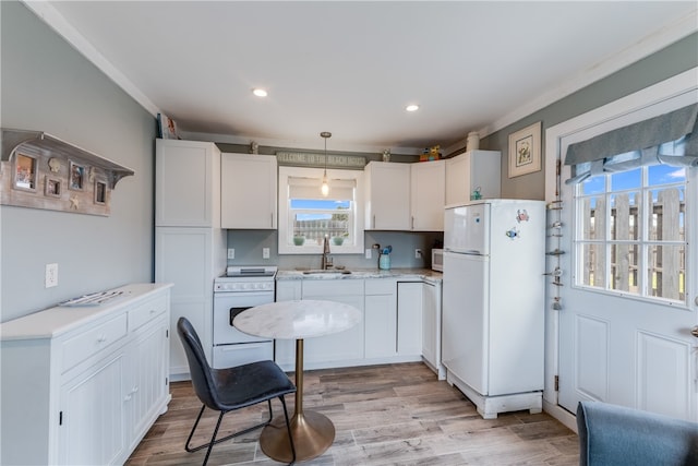 kitchen with pendant lighting, sink, light hardwood / wood-style floors, white cabinets, and white appliances