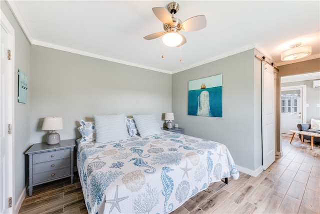 bedroom featuring ornamental molding, hardwood / wood-style floors, a barn door, and ceiling fan