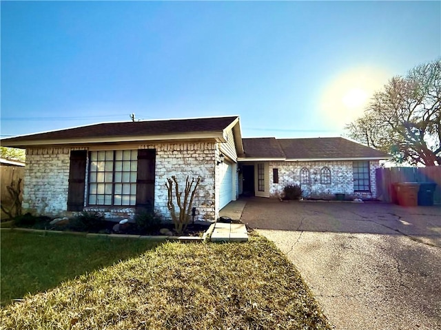 ranch-style house with stone siding, a front lawn, concrete driveway, and a garage