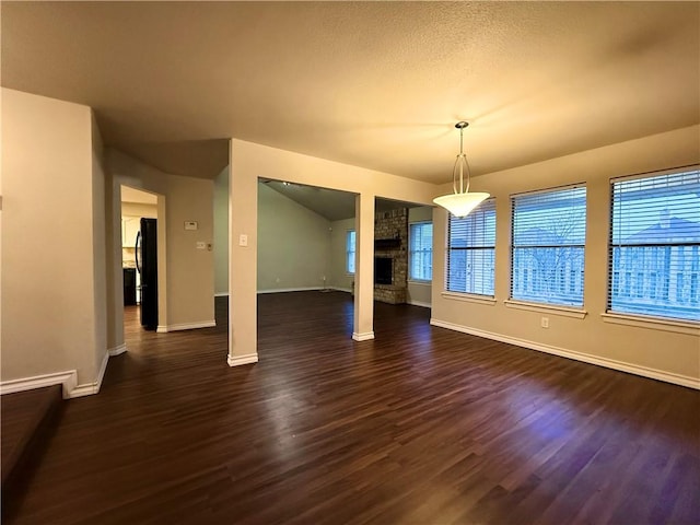 unfurnished dining area with a stone fireplace and dark hardwood / wood-style floors