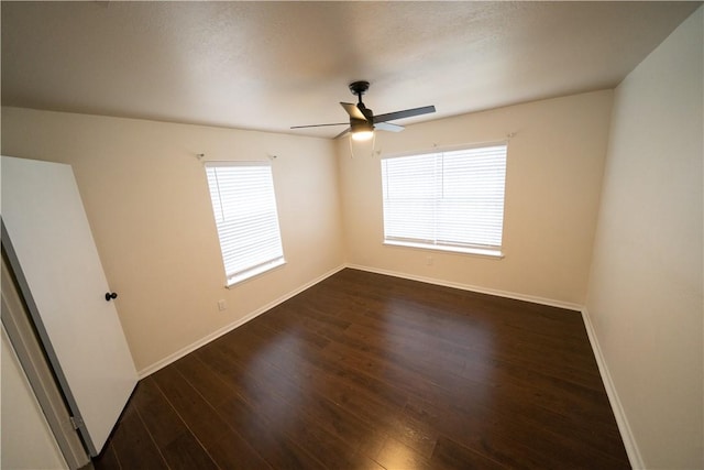 empty room with dark hardwood / wood-style floors, ceiling fan, and a healthy amount of sunlight