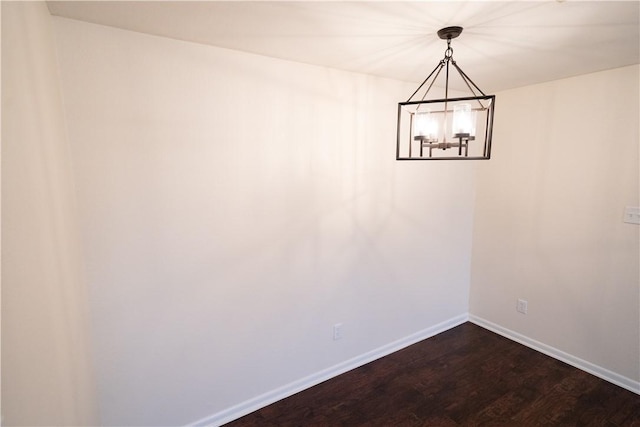 spare room featuring dark hardwood / wood-style floors and a notable chandelier