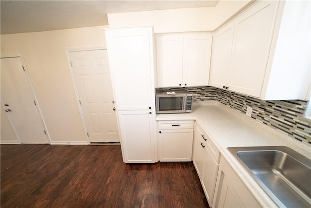 kitchen featuring decorative backsplash, sink, white cabinets, and dark hardwood / wood-style floors