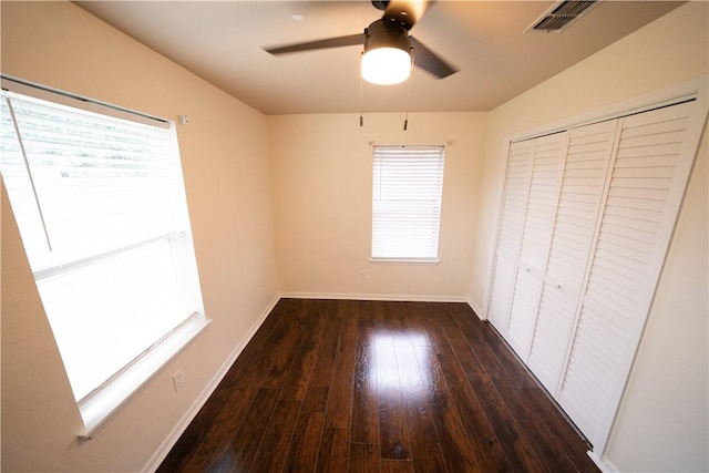 unfurnished bedroom featuring ceiling fan, dark hardwood / wood-style floors, and a closet