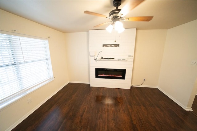 unfurnished room with ceiling fan, a fireplace, and dark wood-type flooring