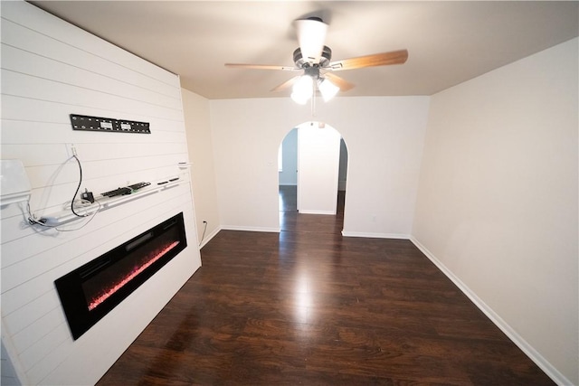 unfurnished living room featuring dark hardwood / wood-style flooring, ceiling fan, and a large fireplace