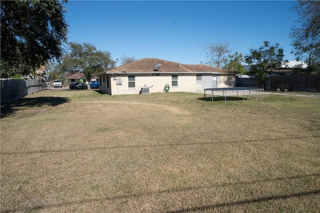 rear view of property featuring a yard and a trampoline