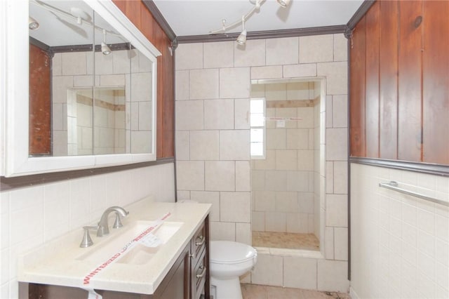 bathroom featuring tile walls, vanity, ornamental molding, tiled shower, and toilet