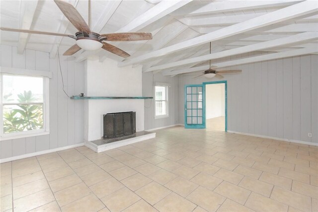 unfurnished living room featuring ceiling fan, light tile patterned floors, wood walls, and lofted ceiling with beams