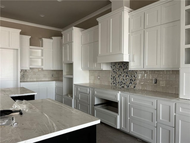 kitchen with white cabinets, decorative backsplash, light stone counters, and ornamental molding