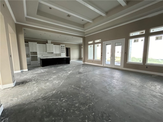 unfurnished living room featuring plenty of natural light, a raised ceiling, and french doors