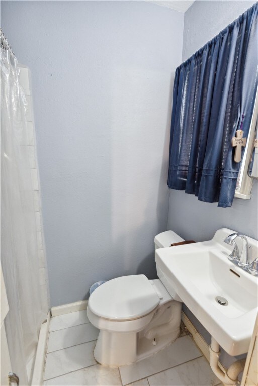 bathroom with toilet, tile patterned floors, and curtained shower