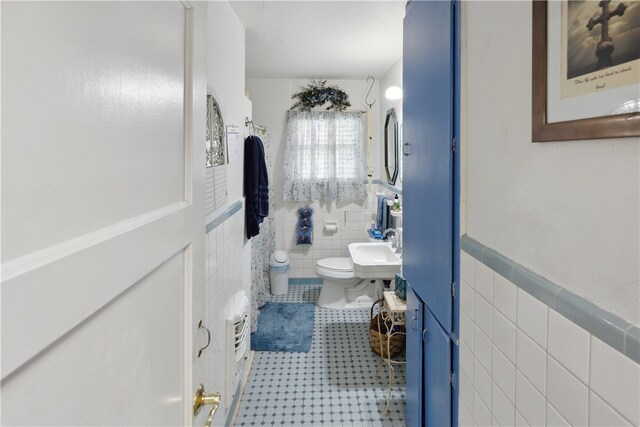 bathroom with toilet, tile walls, and sink