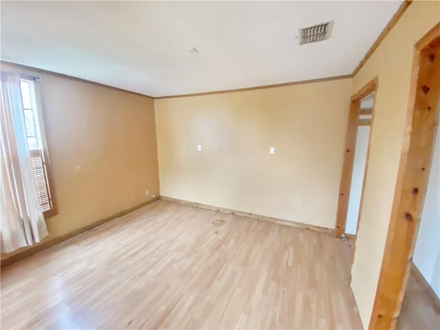 empty room featuring ornamental molding and light wood-type flooring