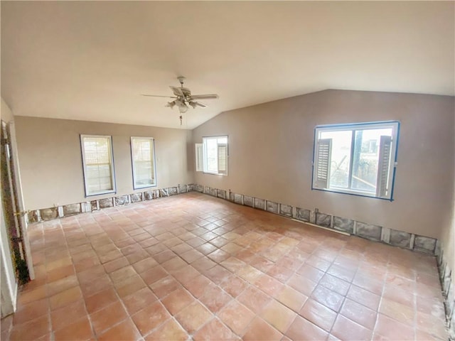 tiled empty room with ceiling fan and vaulted ceiling