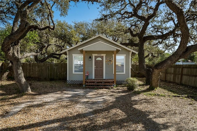 view of front facade with entry steps, fence, and dirt driveway