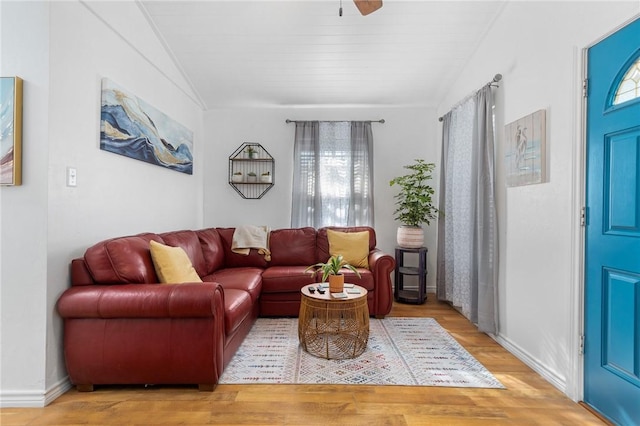 living room featuring vaulted ceiling, ceiling fan, wood finished floors, and baseboards