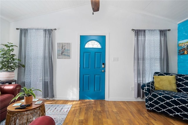 foyer with wood-type flooring, lofted ceiling with beams, and baseboards