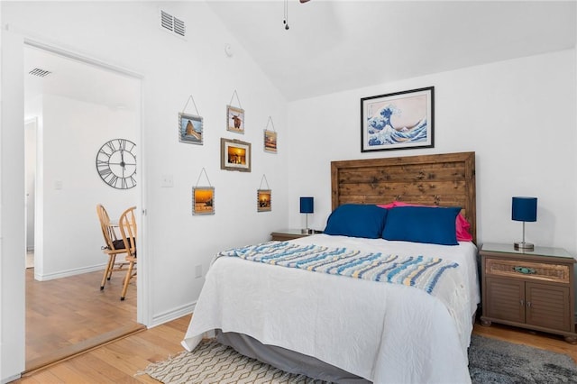 bedroom with visible vents, vaulted ceiling, baseboards, and wood finished floors