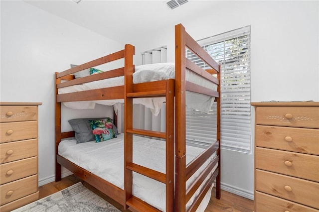 bedroom with light wood-type flooring, visible vents, and baseboards