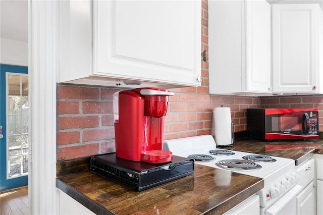 interior details featuring dark countertops, electric stove, white cabinetry, and decorative backsplash