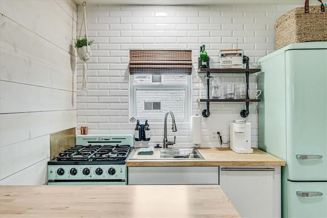 kitchen featuring stainless steel gas stove, sink, and white fridge