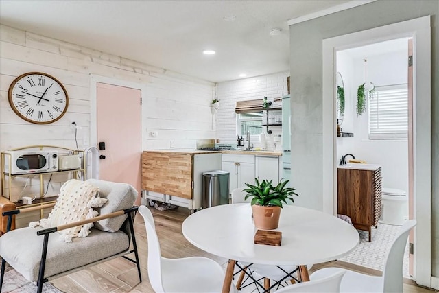 dining room with wooden walls, sink, and light hardwood / wood-style floors